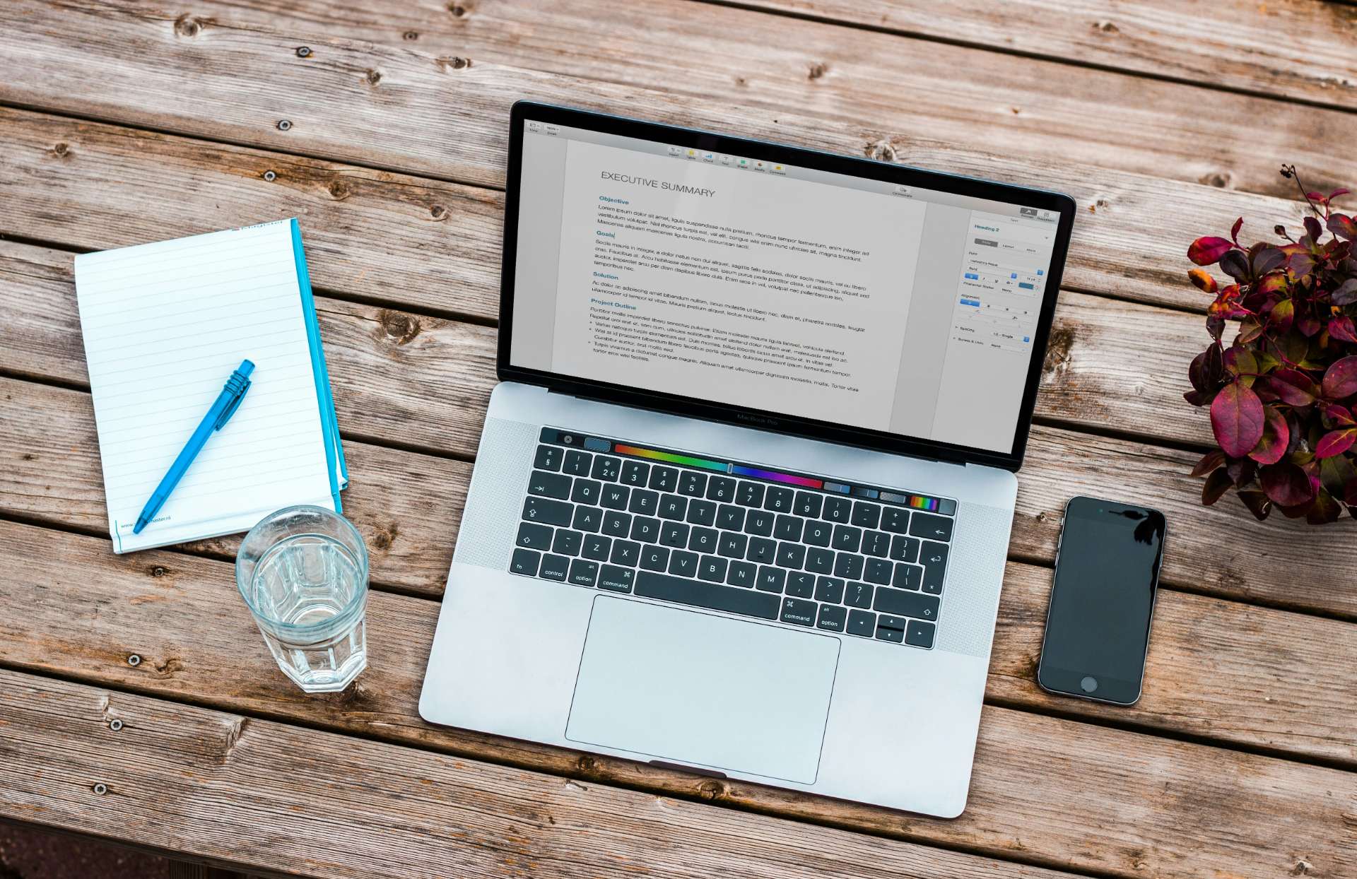 Laptop with notebook and glass of water next to it